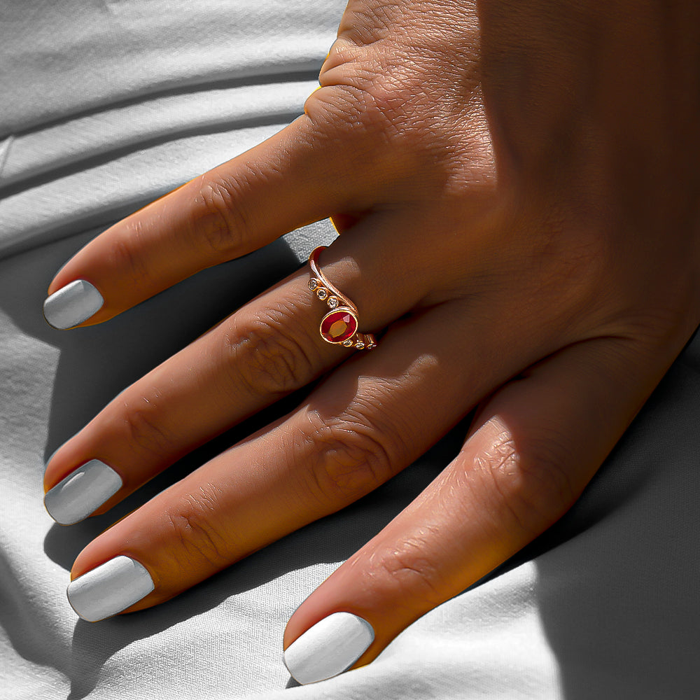 Kenarlarında pırlanta taşları ve ortasında oval kesim yakut taşı bulunan vintage tasarım yüzüğün kadın model parmağındaki görüntüsü