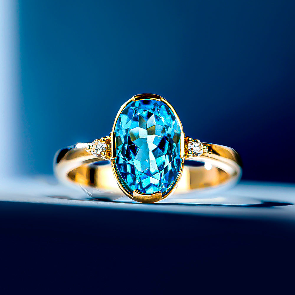 2.70 Karat Okyanus Pırlantalı Mavi Topaz Yüzük mavi bir zeminin üzerinde ışıldıyor