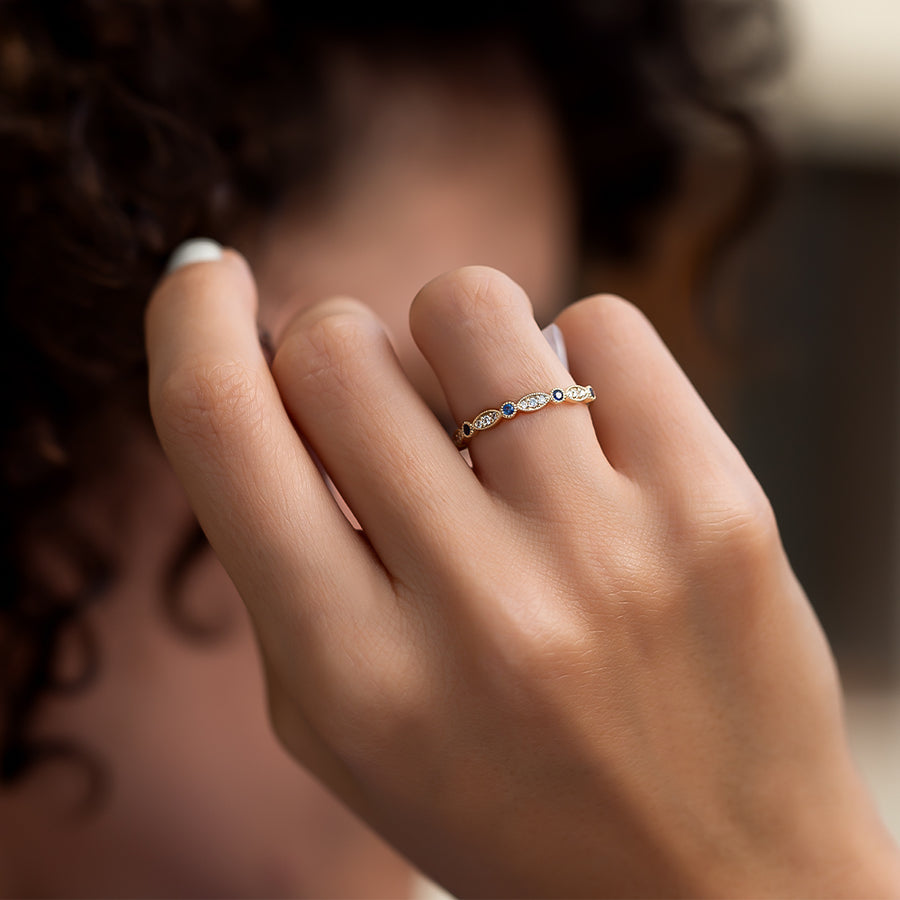 safir ve pırlanta taşlarından oluşan vintage tasarım altın yüzüğün bir kadın modelin üzerindeki duruşunun uzaktan görünümü 