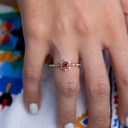 vintage tarzında ortasında turmalin taşı ve kenarlarında pırlantalar bulunan altın rengi yüzüğün kadın modelin parmağındaki görünümü