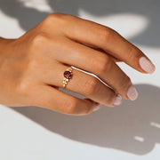 kenarlarında toplamda 10 adet pırlanta ve ortasında 1 adet turuncu turmalin taşı bulunan vintage altın yüzüğü parmağına takmış bir kadın modelin elinin fotoğrafı
