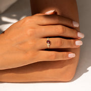 kenarlarında toplamda 10 adet pırlanta ve ortasında 1 adet turuncu turmalin taşı bulunan vintage altın yüzüğü parmağına takmış bir kadın modelin elinin karşıdan görünümü