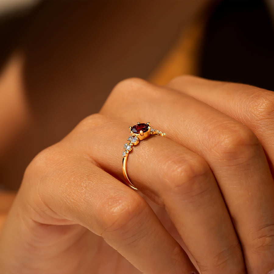 kenarlarında toplamda 10 adet pırlanta ve ortasında 1 adet turuncu turmalin taşı bulunan vintage altın yüzüğü parmağına takmış bir kadın modelin elinin alt açı görünümü
